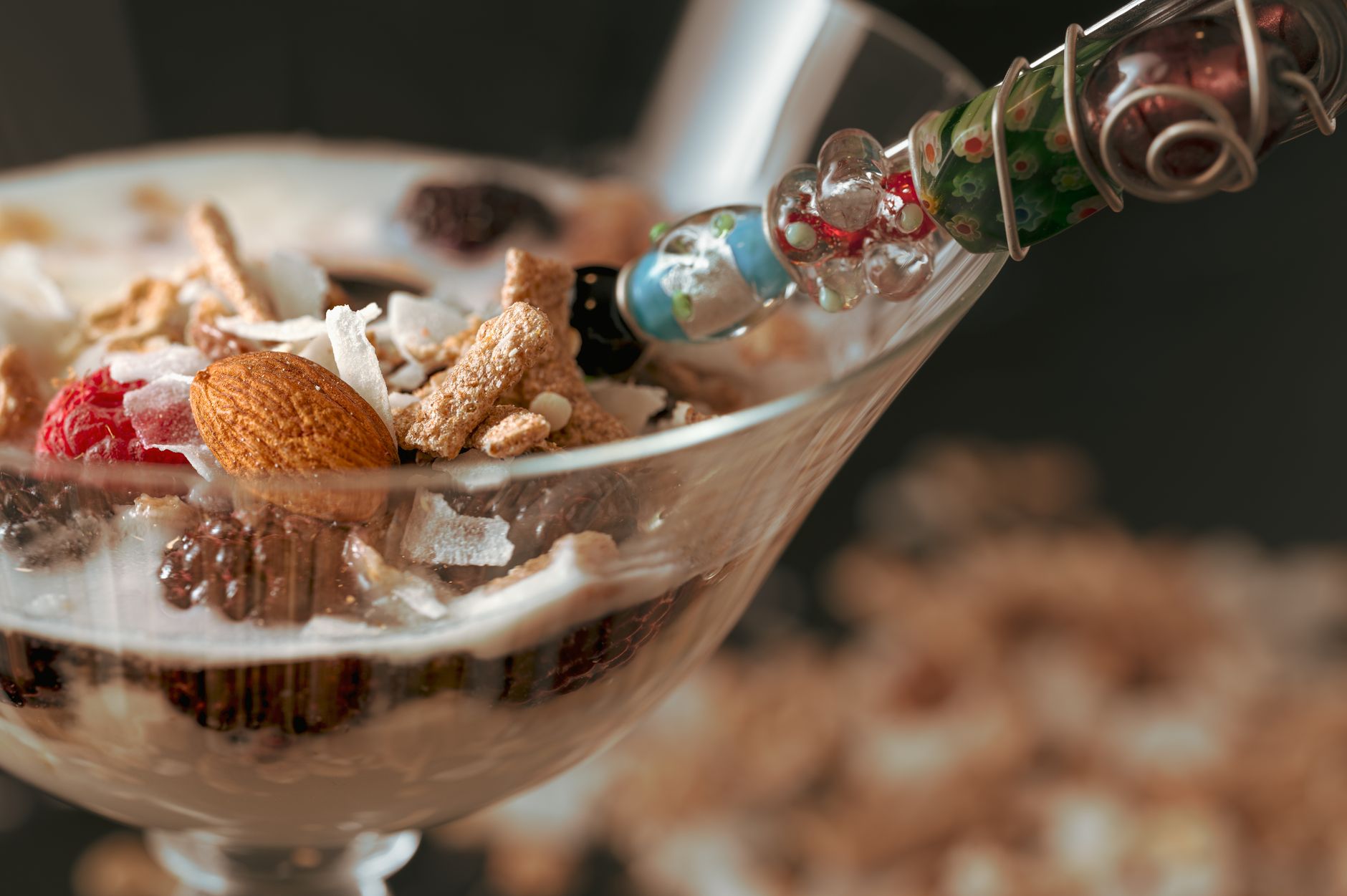 Delicious yogurt parfait with granola, almonds, and raspberries in a glass cup.